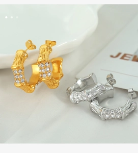 Close-up detail of C-shaped bamboo earrings with zircon accents in gold and silver
