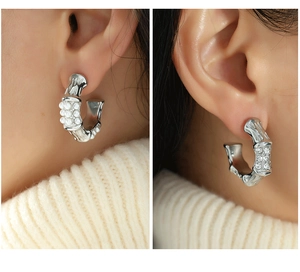 Detailed view of bamboo-style C-shaped silver earrings with pearls and crystal inlay