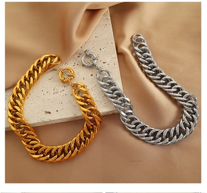 Dettaglio di bracciali a catena cubana spessa in oro e argento su seta con chiusura
