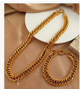 Dettaglio del set collana e bracciale a maglia cubana dorata su sfondo di seta calda