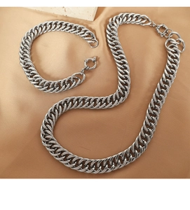 Dettaglio di collana a maglia cubana argentata e bracciale su raso color champagne
