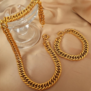Set collana e bracciale a maglia cubana dorata lucida su sfondo di seta pregiata