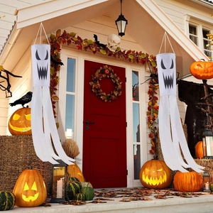 Set of two Halloween ghost windsocks hanging on a porch with festive decorations