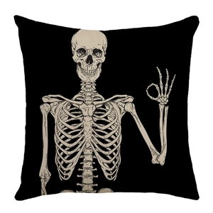Detail of black throw pillow case featuring a beige skeleton hand making an OK sign