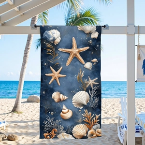 Blue microfiber beach towel with ocean starfish and coral print on a sunny beach