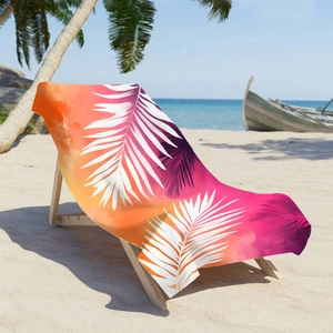 Microfiber beach towel with palm leaf print and orange-pink gradient on a beach lounge chair