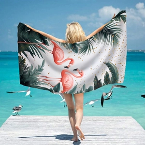 Microfiber beach towel with pink flamingos and palm leaves on a sunny seaside dock