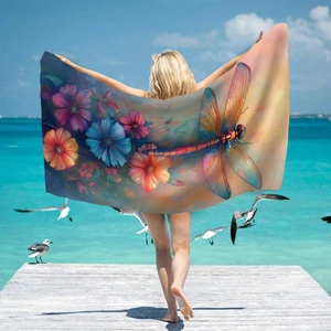 Microfiber beach towel featuring dragonfly and floral print held by model on scenic pier