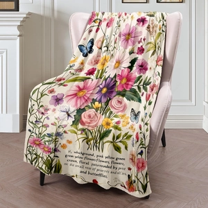 Floral flannel throw blanket with butterflies draped over a pink velvet chair in a cozy room