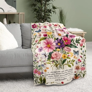 Floral flannel blanket with pink roses and butterflies draped over a modern grey sofa