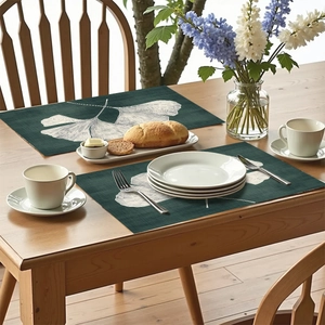 Deep green ginkgo leaf place mats on wooden table with elegant white dinnerware