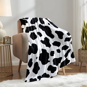 Gemütliche Flanell-Kuscheldecke mit Kuhmuster auf Sofa in moderner Inneneinrichtung