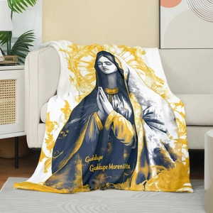 Detail of the soft flannel Virgin of Guadalupe throw blanket draped over a cozy sofa