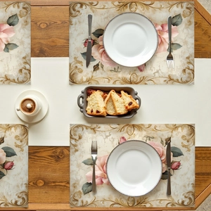 Detail shot of four Victorian pink rose placemats with gold floral borders on a wood table