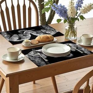 Détail de sets de table noirs avec motifs d'éléphant et mandala blancs sur table en bois