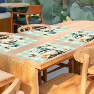 Set of 4 green plaid gnome placemats with daisies and butterflies on a wooden table
