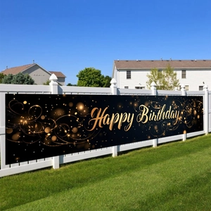Detail of black and gold Happy Birthday banner hanging on white garden fence