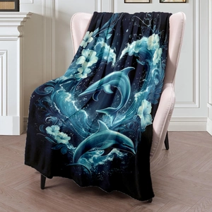 Deep blue flannel blanket featuring leaping dolphins and hibiscus flowers on a soft pink chair