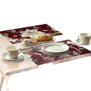 Set of 2 Christmas poinsettia table mats with red floral pattern on light wood table