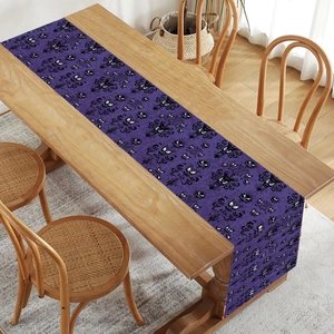 Purple Halloween table runner with gothic monster eyes on a rustic wooden dining table