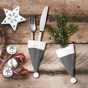 Set mit zwei grauen Besteckhaltern in Weihnachtsmützenform auf festlichem Holztisch