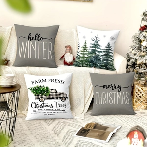 Set of four Christmas throw pillow covers with tree and truck patterns on a cozy sofa