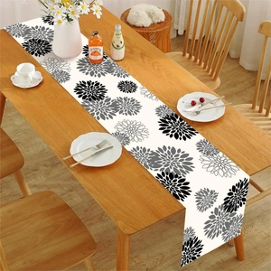 Close-up of floral table runner with black and grey dahlia patterns on a wooden dining table