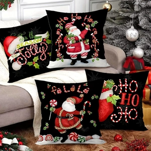 Set of four black Christmas pillow covers with Santa and holiday greetings on a sofa