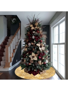 Detailed view of the gold Christmas tree skirt with white snowflake patterns on wood floor