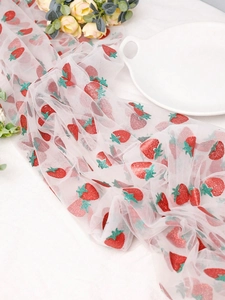 Close-up of white mesh fabric featuring red glitter strawberry prints for table decor