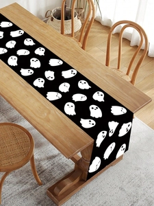 Detail of cute white ghost patterns on a black festive table runner for Halloween