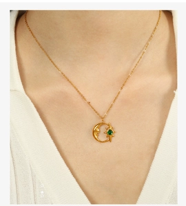 Detalle del collar con colgante de luna y estrella dorada con gema verde en modelo