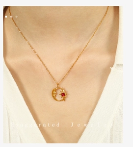 Detalle del collar con colgante de sol y luna dorados con gema roja en una modelo