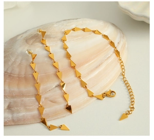 Detailed view of polished golden geometric triangle jewelry set displayed on a seashell