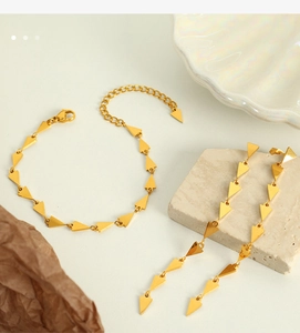 Macro detail of golden geometric triangle necklace set with textured stones and shell tray
