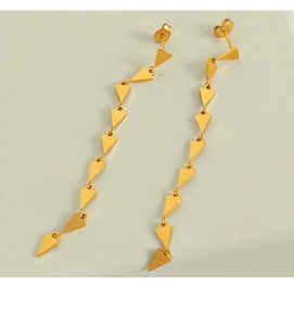 Detail of long gold geometric triangle fringe earrings on a minimalist display