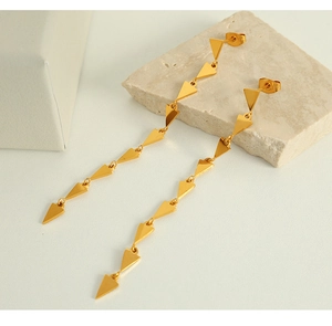 Detailed close-up of golden triangular tassel earrings with cascading geometric links