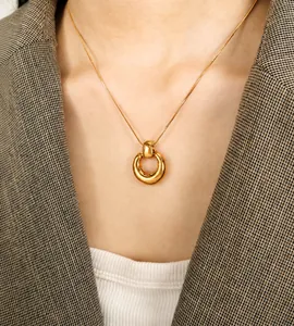 Detail of minimalist 18K gold plated circle pendant with sleek snake chain on a model