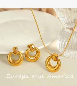 Detailed shot of 18K gold plated hoop earrings and snake chain necklace on white plate