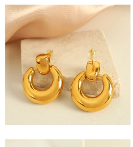 Macro view of polished 18K gold-plated hoop earrings with square clasp on marble