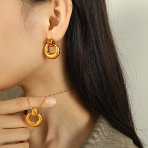 Polished 18K gold circular pendant necklace and hoop earring set on female model