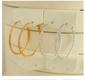 Makroaufnahme von gold- und silberfarbenen Creolen mit Diamond-Cut-Textur und Glanz