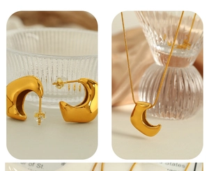 Detail of 18K gold plated C-shaped earrings and horn pendant necklace on satin