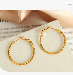 Detailansicht großer goldener Creolen mit gedrehter Textur und Diamantschliff-Muster