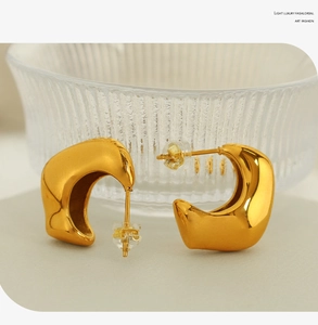 Polished 18K gold plated C-shaped hoop earrings on elegant textured display base
