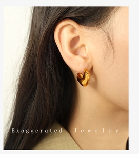 Close-up of polished 18K gold-plated chunky C-shaped hoop earrings on a female model