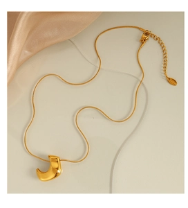 Macro detail of a 18K gold-plated stainless steel snake chain necklace with a bean pendant