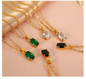 Detailed macro view of gold oval gemstone necklaces with emerald, clear, and black stones