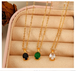 Detailed shot of oval gemstone necklaces in black, green, and clear on velvet