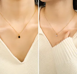 Close-up of elegant gold necklaces with black oval gem and clear teardrop zircon pendant